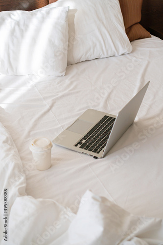 there is a laptop on the bed, next to it lies a bouquet of flowers and a mug of coffee
