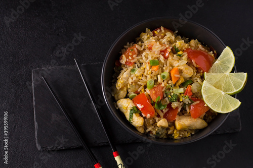 Khao Pad, fried rice with vegetables, meat and eggs, with fresh cucumbers, tomatoes, with chopsticks.