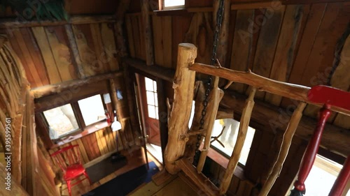 View of the interiors of an off grid mini house in the woodlands from the first floor stair banister. Camera rotates revealing furniture and decor. photo