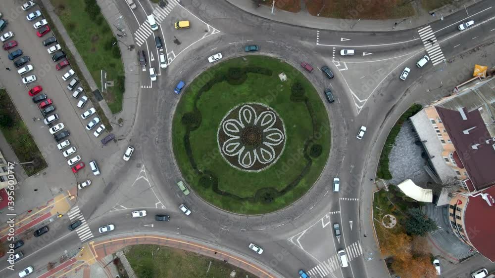 4k aerial view of roundabout road with circular cars in small european city at cloudy autumn day