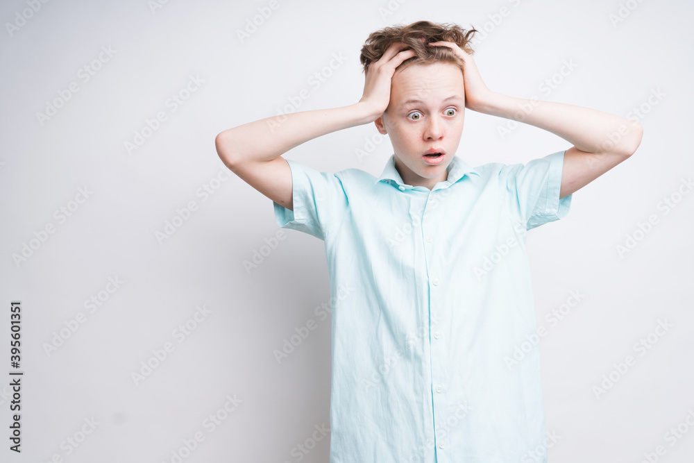 A caucasian boy on a white background is anxious about something A caucasian boy on a white background is anxious about something
