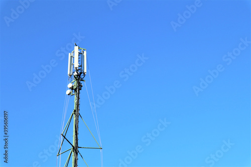 Telecommunication tower with antennas against blue sky background with copy space.