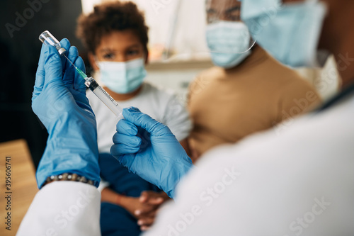 Close-up of a pediatrician preparing vaccine for a child.