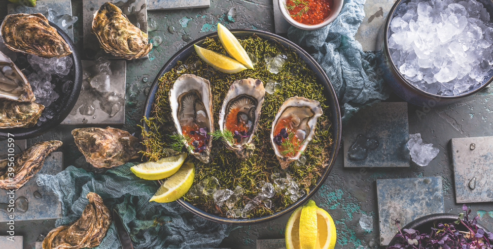 Fototapeta premium Leckere Austern auf Eis mit Zitrone. Raffiniert mit Kräutern und Lachskaviar.