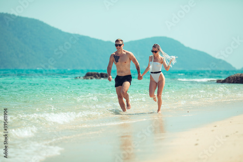 A romantic couple on the beach in a swimsuit, beautiful sexy young people. girl with  white dreadlocks and a man with a tattoo, having fun on the beach. Phuket. Thailand. © Semachkovsky 