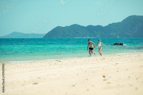 A romantic couple on the beach in a swimsuit, beautiful sexy young people. girl with  white dreadlocks and a man with a tattoo, having fun on the beach. Phuket. Thailand.