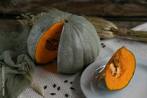Pumpkin cut on a white plate with light textile and wooden background. Rustic style