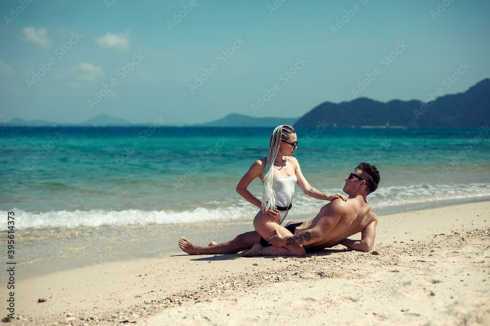 Sensual young couple in swimsuits laying on the sand by the sea over sky and tropical island background. Phuket. Thailand. Sensual young couple in swimsuits laying on the sand by the sea over sky and tropical island background. Phuket. Thailand.