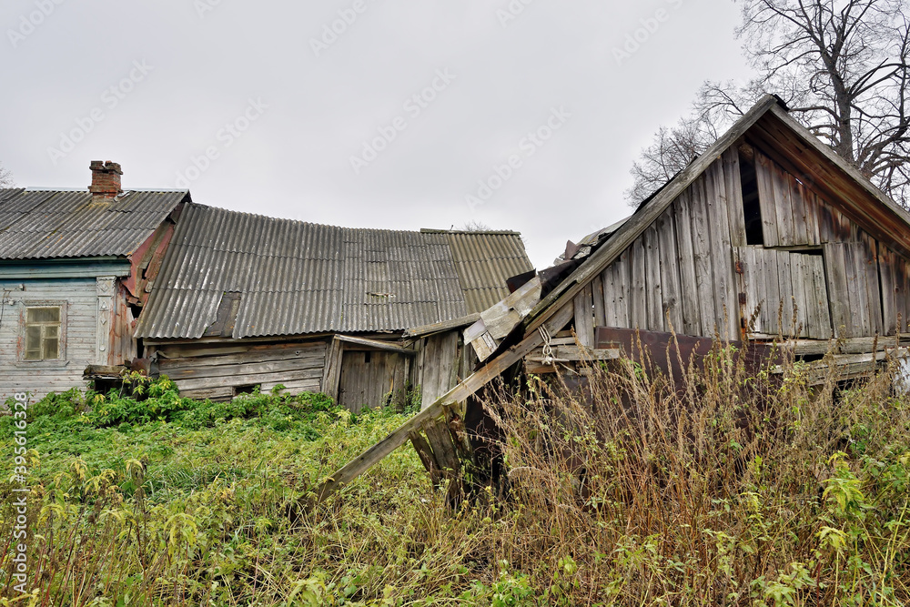 Ruined wooden farmhouse and barn. Abandoned village house. Concept: devastation, depression, decline of rural life Ruined wooden farmhouse and barn. Abandoned village house. Concept: devastation, depression, decline of rural life