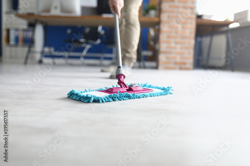 Professional cleaning services for complex cleaning of premises. Man wash floor Mop with damp cloth indoors.
