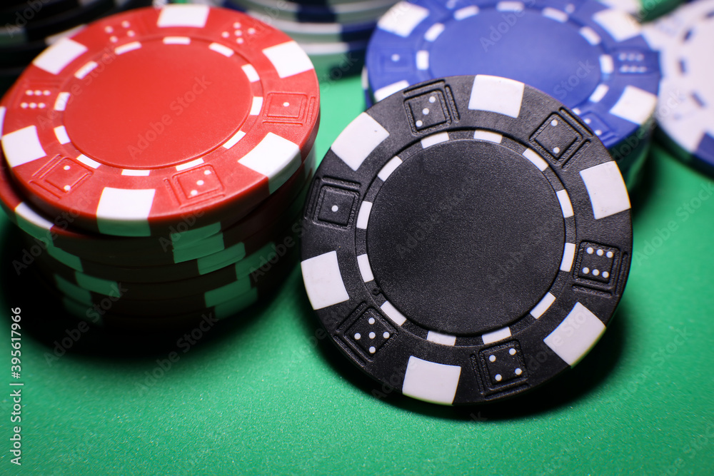Different poker playing chips on a green table against black background. Online gaming. Different poker playing chips on a green table against black background. Online gaming.