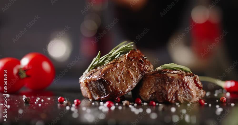 Chef decorating a plate with freshly grilled meat . Cooker adding a piece of rosemary with tweezers on top of steak - food art gourmet dinner 4k footage close up