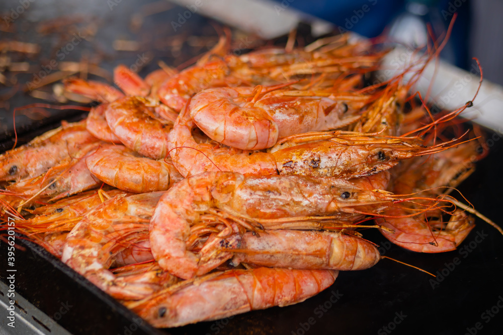 Process of cooking fresh red langoustine shrimps, prawns on grill at summer local food market - close up. Outdoor cooking, barbecue, gastronomy, seafood, cookery, street food concept