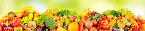 Wide pattern of ripe fruits and vegetables on green background.