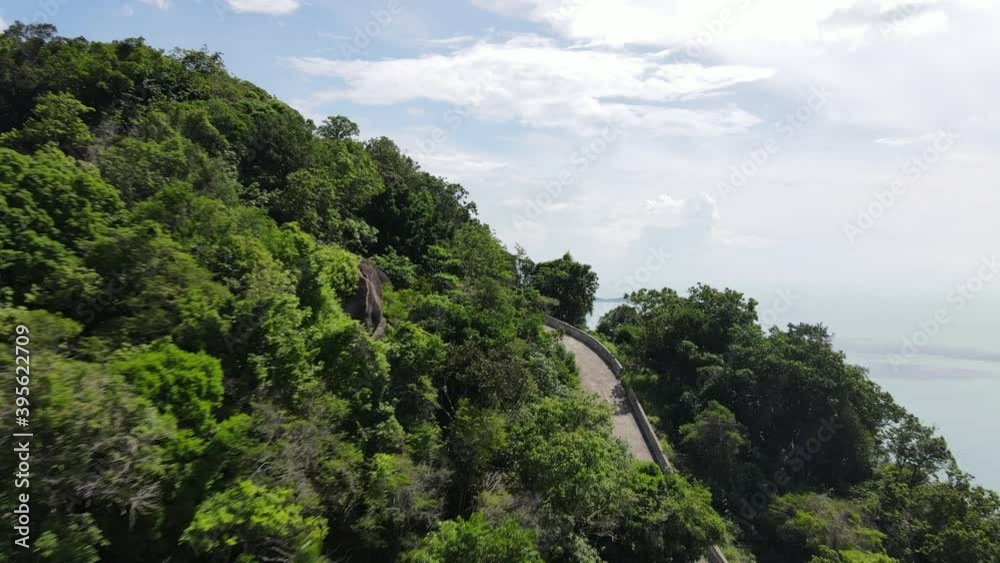 Tropical island mountains reveal aerial view of the ocean and a village or a city over the trees on a hill. Tropical island mountains reveal aerial view of the ocean and a village or a city over the trees on a hill.
