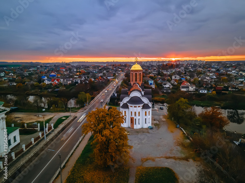 HDR aerial view of old church near river and bridge in small european city at epic sunset