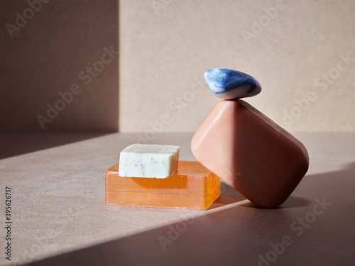 empilement de savons artisanaux pour le corps ou les mains, soins d'hygiène écologiques sur un fond neutre baigné de soleil