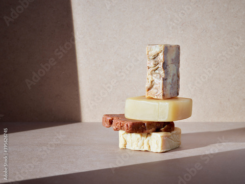 empilement de savons artisanaux pour le corps ou les mains, soins d'hygiène écologiques sur un fond neutre baigné de soleil