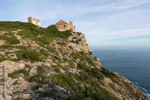 Ruin buildings in Cape Espichel landscape with atlantic ocean and cliffs, in Portugal
