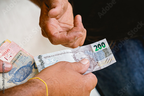 Real, Real Brasileiro, Reais, Dinheiro, Brasil. Homem fazendo um pagamento com cédulas brasileiras. Nota de 200 Reais em destaque. photo