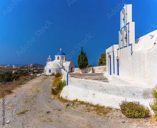 A view of a small church and bell tower close to the town of Akortiri in Santorini in summertime photo