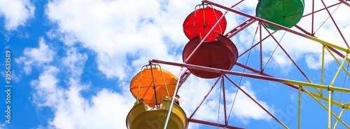 Vintage old fashioned bright multicolored Ferris wheel against a blue cloudy sky. Copy space. Banner.	