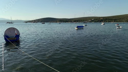 Time lapse footage of moored fishing boats and yachts, windmills farm in touristic Aegean town called 