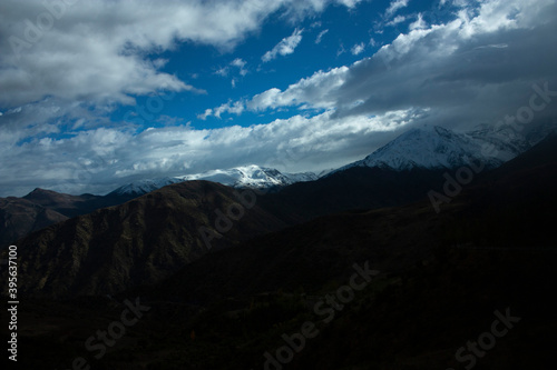 .Christmas atmosphere in the Andes Mountains in Chile Country Timid ray of sun that crosses the cloudy sky to illuminate part of the mountain crown
