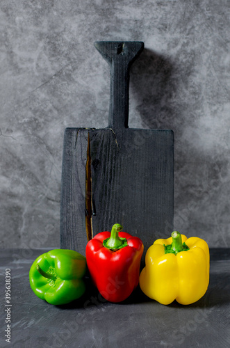 Red, yellow and green bell pepper paprika on a grey background
