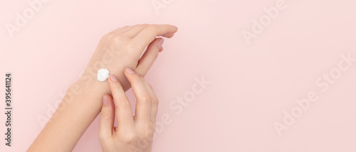 Well-groomed hands with cream on a light pink background. Banner  copy space on the right.