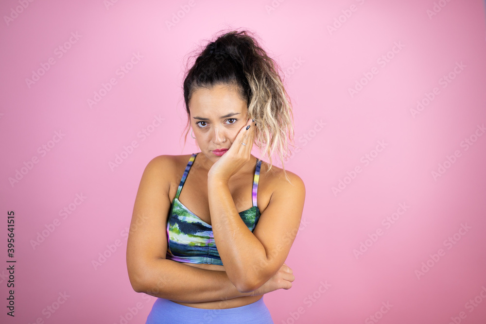 Young beautiful woman wearing sportswear over isolated pink background thinking looking tired and bored with crossed arms Young beautiful woman wearing sportswear over isolated pink background thinking looking tired and bored with crossed arms