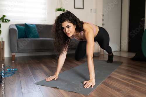 Hispanic woman training with a cardio workout at home