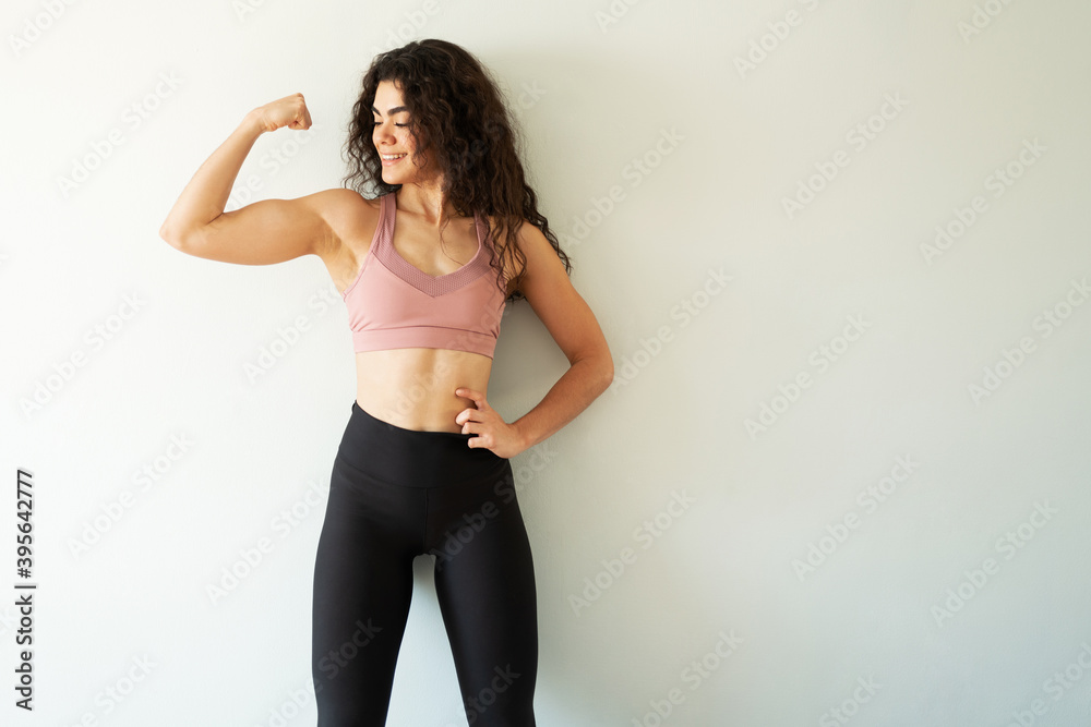 Fit young woman showing off her arm muscles and smiling Fit young woman showing off her arm muscles and smiling