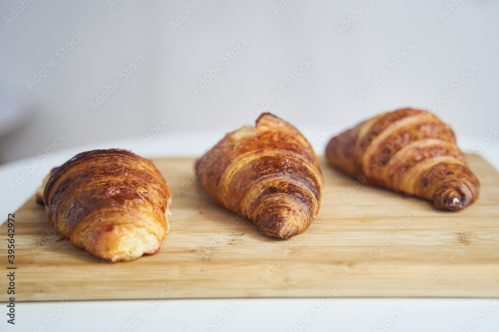 Close up of golden croissants on a wooden tray Close up of golden croissants on a wooden tray