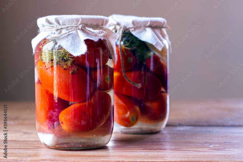 Homemade pickled tomatoes in glass jars on rustic wooden background. Fermented tomatoes in transparent glass. Homemade canned tomatoes. Homemade pickled tomatoes in glass jars on rustic wooden background. Fermented tomatoes in transparent glass. Homemade canned tomatoes.