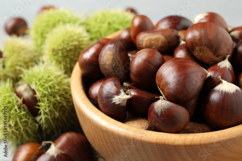 Fresh sweet edible chestnuts in wooden bowl, closeup