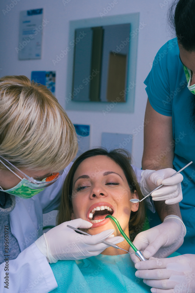 Professional male and female dentists examining woman's teeth in dental