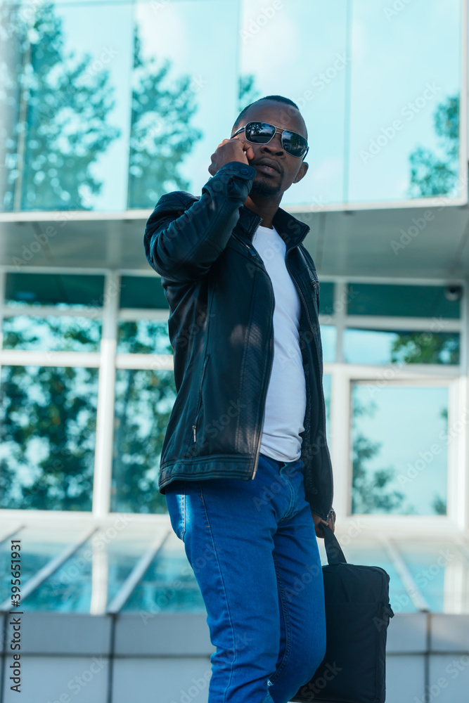 Fototapeta premium Afro American young businessman talking on his mobile phone outside the office building