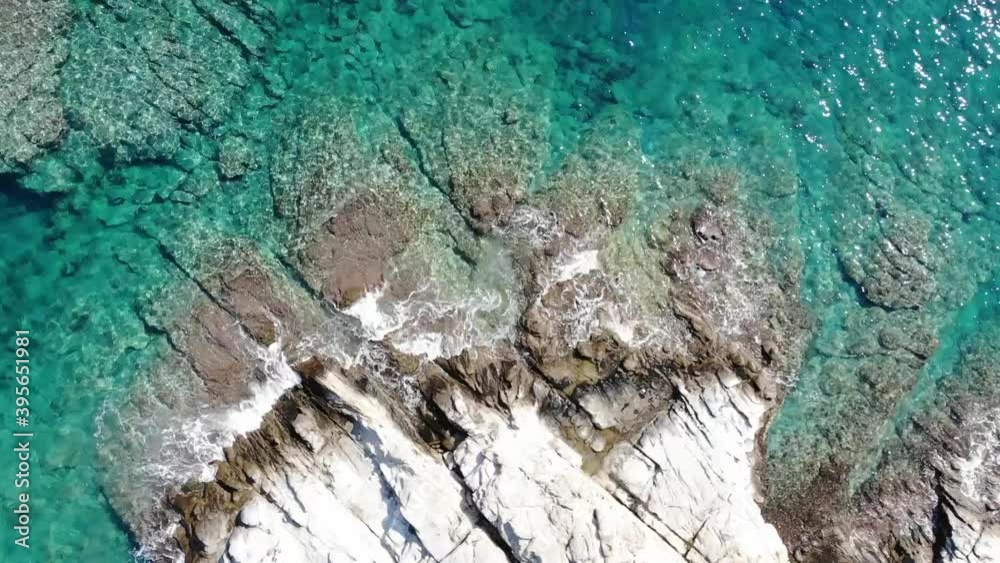 Top down view of white cliffs with crystal clear water and sizeable waves splashing over the sea coast in Kavala, Greece. Top down view of white cliffs with crystal clear water and sizeable waves splashing over the sea coast in Kavala, Greece.