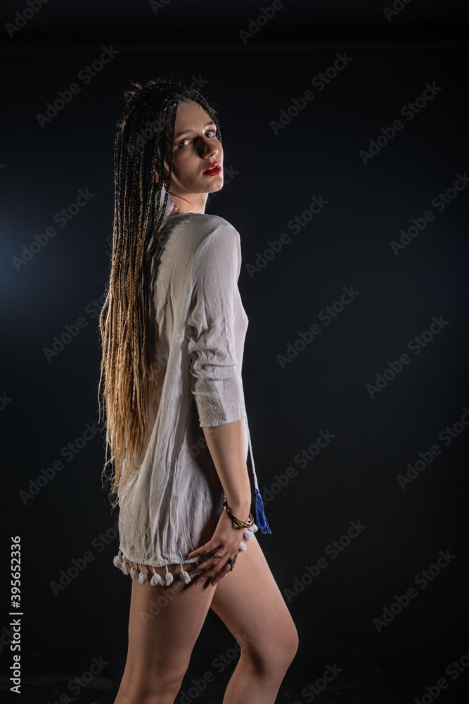 Attractive female feminist waring tribal short white dress. The isolated photo on a black background. Woman queen concept. Attractive female feminist waring tribal short white dress. The isolated photo on a black background. Woman queen concept.