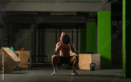 Fit man throwing medicine ball doing ball slam against gym floor or shoulder press exercise.. photo