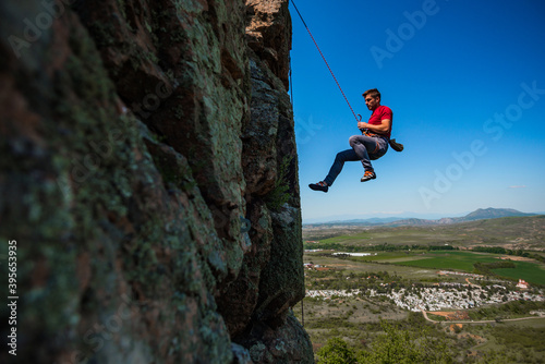 Male rock climber hanging over the abyss
