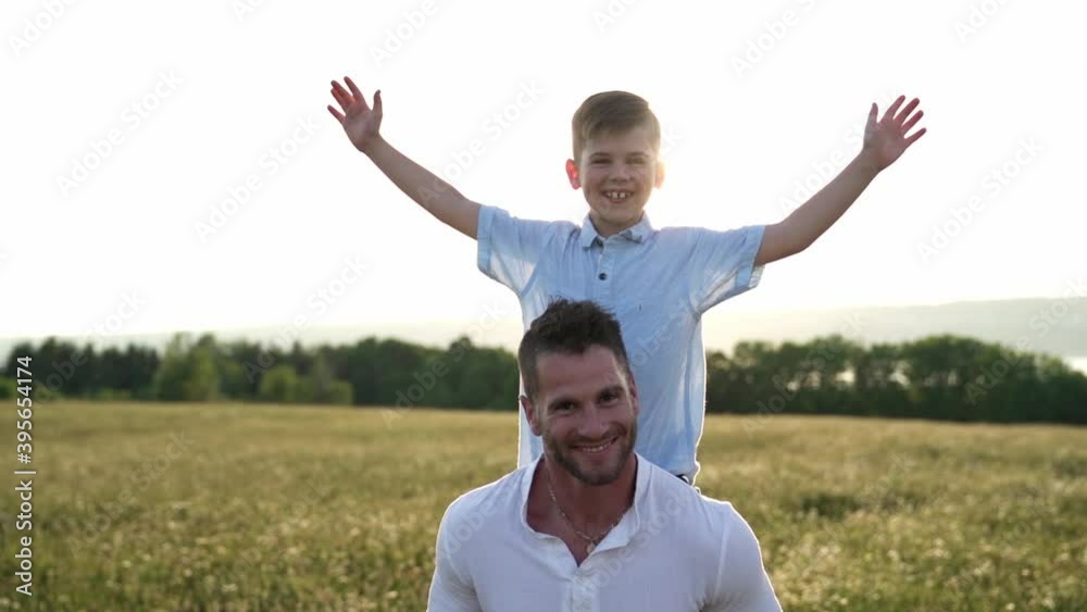 happy family of father and child on field at the sunset having fun on back with hand high happy family of father and child on field at the sunset having fun on back with hand high