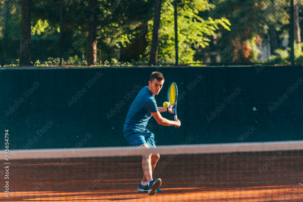 Professional equipped male tennis player beating hard the tennis ball with a backhand Professional equipped male tennis player beating hard the tennis ball with a backhand
