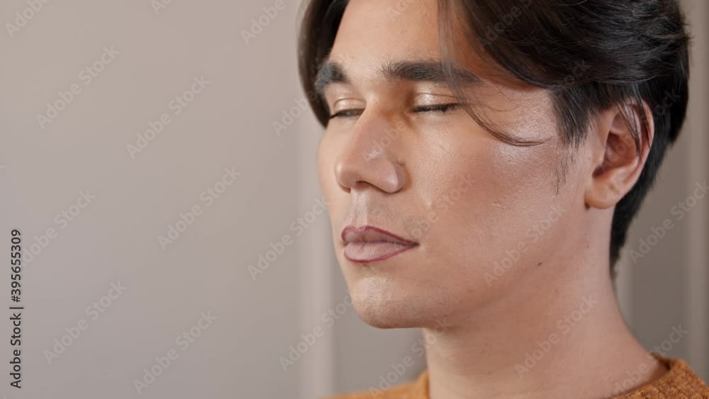 Makeup studio - makeup artist applying dark red lip pencil over the lip contour of male model Makeup studio - makeup artist applying dark red lip pencil over the lip contour of male model