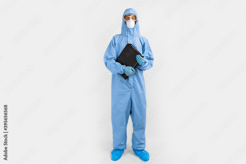 male doctor, dressed in a protective suit against coronavirus, glasses, mask and gloves, writes documents on an isolated white background. coronavirus, covid 19, medicine male doctor, dressed in a protective suit against coronavirus, glasses, mask and gloves, writes documents on an isolated white background. coronavirus, covid 19, medicine