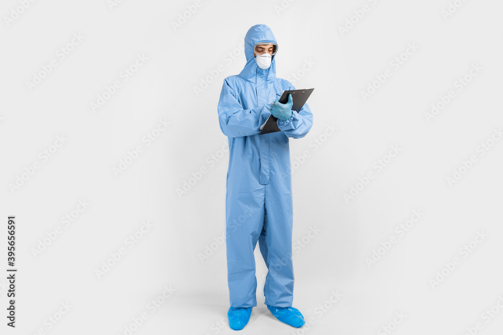 male doctor, dressed in a protective suit against coronavirus, glasses, mask and gloves, writes documents on an isolated white background. coronavirus, covid 19, medicine