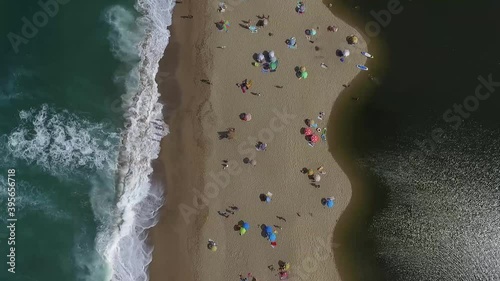 Top down view from Veleka Beach, Sinemorets,   filled with colorful umbrellas during the Festival of kites. Strong waves splashing over the beach.