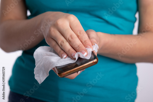 Woman's hands cleaning smartphone mobile phone with wet wipes