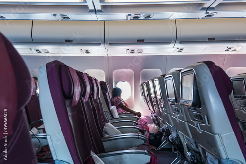 An Indian woman looking at the window of airplane of Qatar Airways in the blue sky flying to Doha
